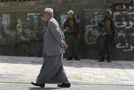 شيخ فلسطيني يمر امام جنديين اسرائيليين في القدس الشرقية