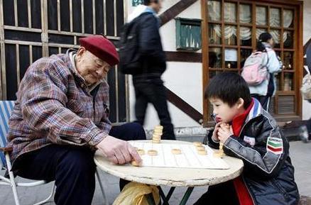 طفل يلعب شرطرنج صيني مع رجل مسن في ضاحية بشنغهاي