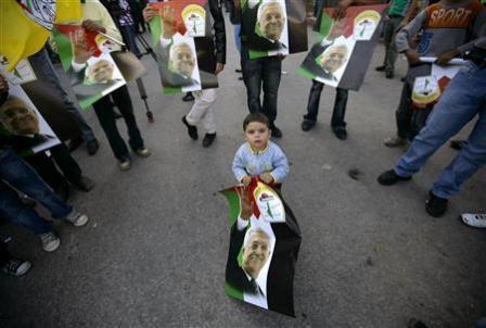 طفل فلسطيني يحمل ملصقا للرئيس الفلسطيني محمود عباس في رام الله