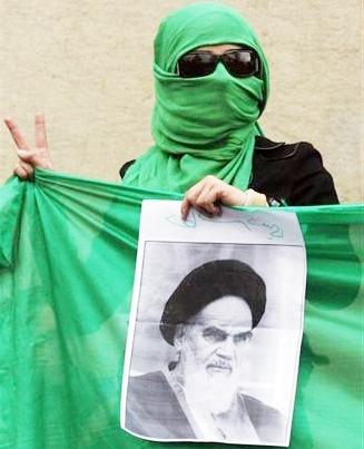 إيراني ملثم يحمل صورة مؤسس الجمهورية الإسلامية الإيرانية آية الله روح الله الخميني خلال مسيرة في وسط طهران .