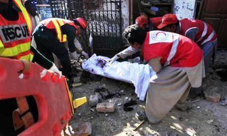 عمال إنقاذ يحملون جثة رجل في موقع هجوم انتحاري عند بوابة النادي الصحافي في بيشاور يوم أمس.