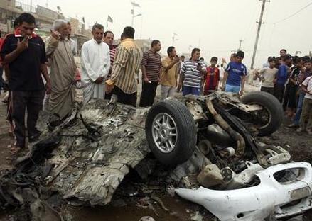 أشخاص ينظرون إلى سيارة محترقة في موقع هجوم بقنبلة بمدينة الصدر في بغداد يوم 29 ابريل  2009 .