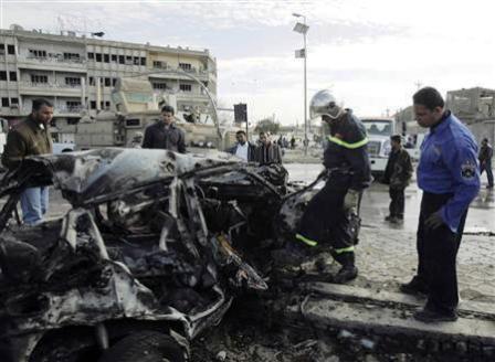 شرطي عراقي يتفقد حطام سيارة دمرت اثر انفجار قنبلة في وسط العاصمة بغداد يوم أمس.
