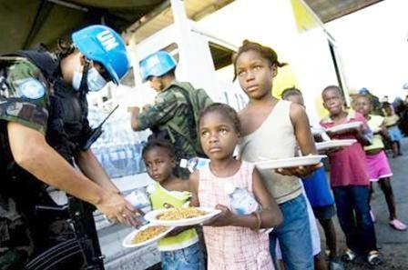 جنديان بوليفيان من قوات حفظ السلام التابعة للأمم المتحدة في هايتي يوزعان مياه ووجبات غذائية على أطفال هايتيين من مشردي الزلزال في سيتي سوليل يوم أمس الأول السبت.