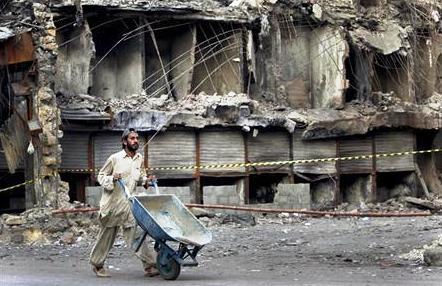 عامل يمر أمام محلات مدمرة في كراتشي يوم أمس.