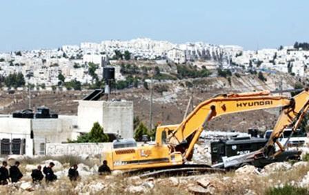 جرافة إسرائيلية تهدم منزلا فلسطينيا بالقدس وفي الخلفية مستوطنة (رامات شلومو)