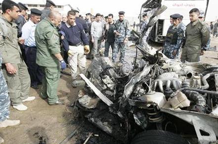 رجال الشرطة العراقية يتفقدون حطام سيارة استخدمت في هجوم بالنجف يوم  أمس السبت.