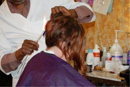 يحلق شعر الزبائن بواسطة عيدان مشتعلة