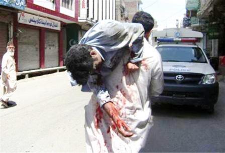 رجل يحمل شخصا أصيب في هجوم انتحاري بقنبلة في وادي سوات بباكستان يوم أمس