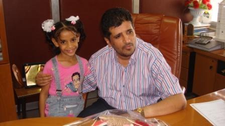 عاتق أحمد علي يحتضن طفلة من مؤسسة (إنسان) أثناء زيارتهم له