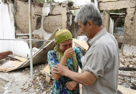 رجل من الاوزبك يهدئ زوجته وسط أنقاض منزلهما الذي اتت عليه النيران أثناء النزاع العرقي في مدينة أوش بجنوب قرغيزستان يوم  أمس الأول الخميس .