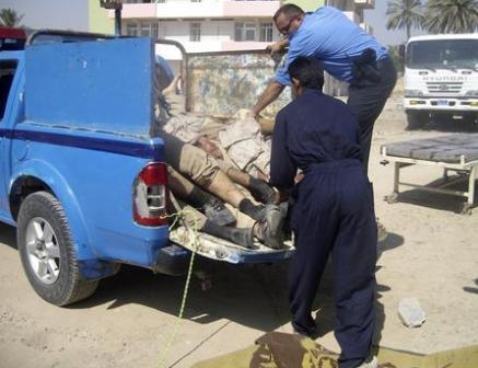 شرطيان ينقلان جثث القتلى في سيارة إلى مستشفى جنوبي بغداد يوم أمس  الأحد .
