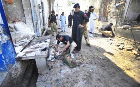 رجال الإنقاذ يجمعون أشلاء القتلى المتناثرة في موقع هجوم انتحاري في بلدة بابي الباكستانية يوم  أمس