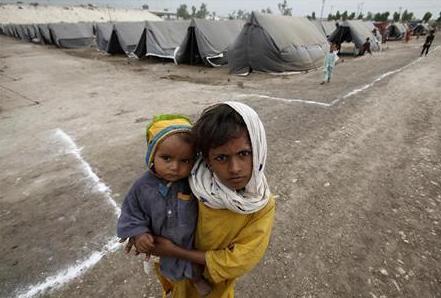 طفلة تحمل شقيقها في مخيم للمتضررين من الفيضانات في إقليم السند في باكستان يوم أمس