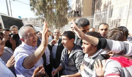 رئيس الوزراء الفلسطيني سلام فياض (الى اليسار) يلوح مودعا شباباً فلسطينيين بعد زيارة قام بها إلى مدرستهم في الضفة الغربية يوم  أمس.