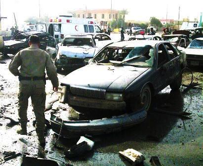 شرطي بجانب سيارات هوجمت بعبوات ناسفة في العراق