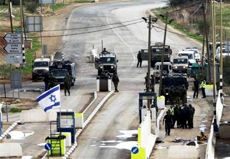 جنود إسرائيليون قرب جثمان فلسطيني عند نقطة تفتيش بالضفة الغربية يوم أمس السبت.