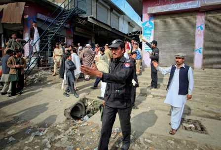أفراد من الشرطة الباكستانية يحاولون إبعاد الناس عن موقع الهجوم الانتحاري في مركز التجنيد التابع للجيش الباكستاني يوم أمس  الخميس.