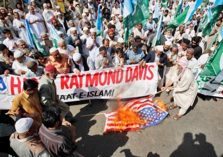 باكستانيون غاضبون يحرقون العلم الامريكي وفي الاطار ريموند ديفيس في حراسة الشرطة الباكستانية لدى خروجه من محكمة في لاهور