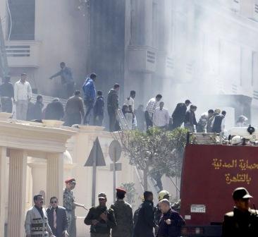 مدنيون ورجال شرطة آمام مبنى يحترق بجوار وزارة الداخلية المصرية في القاهرة أمس.