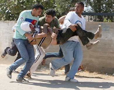 فلسطينيون ينقلون رفيقا لهم أثناء اشتباكات مع مستوطنين أمس