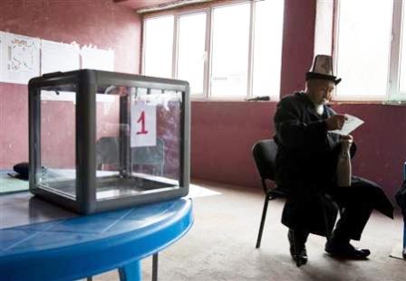 رجل يقرأ ورقة بجوار صندوق انتخابي في مركز اقتراع بمدينة اوش في جنوب قرغيزستان يوم أمس