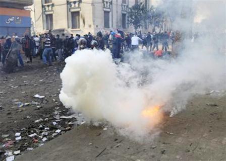 متظاهرون بالقرب من قنبلة غاز مسيلة للدموع اثناء الاشتباكات مع الشرطة